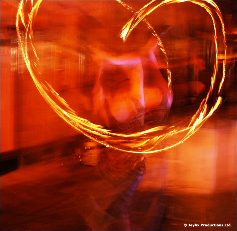 A swirl of orange light trails from a fire prop in a long exposure
