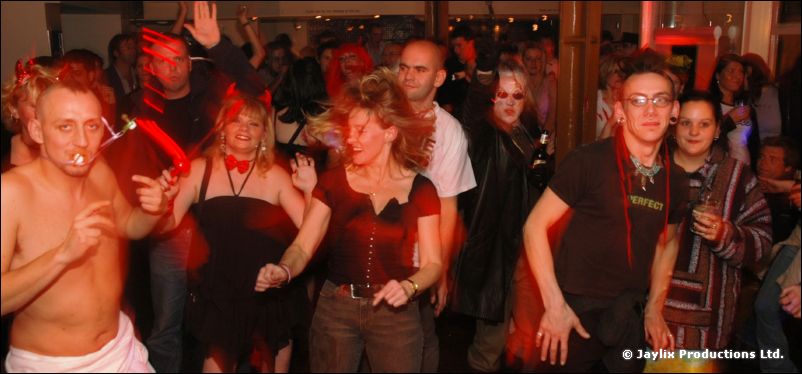 Costumed dancers in a busy bar, a shirtless man with a cigarette in the foreground