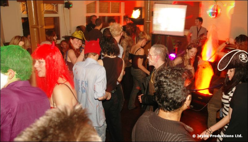 A crowded dance floor with people in wigs and fancy dress, one wearing a pirate hat