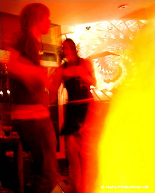 Blurred figures in red and orange light, one appearing to sing into a microphone