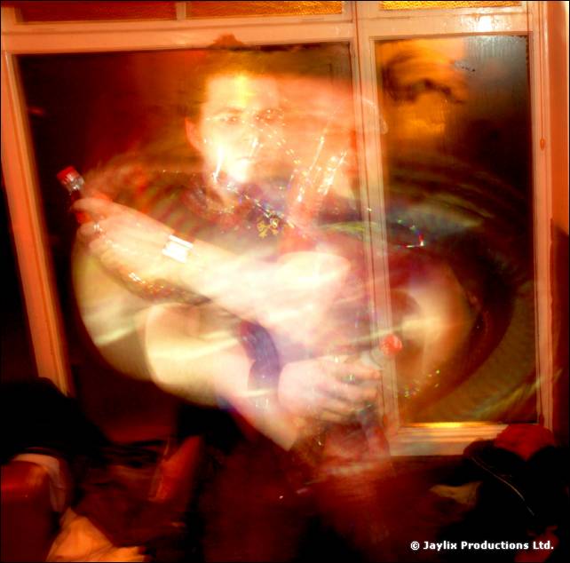 A heavily blurred person holding a bottle in front of a window, with swirling light