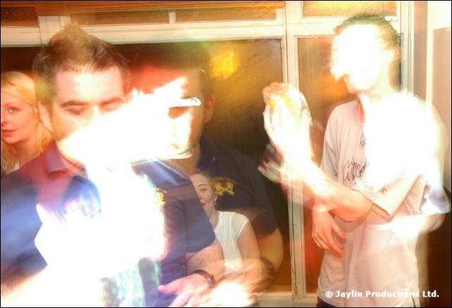 People in a bar with a bright flash of light obscuring one person, another in a blue top behind