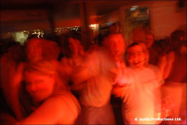 A heavily blurred group of people dancing in a dim orange lit room