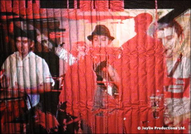 A rippled red screen showing projected people, one in a hat, and red silhouettes