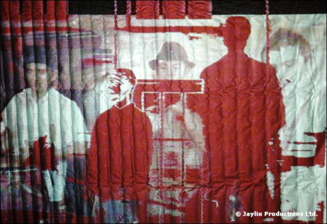A rippled red screen showing projected people, one in a hat, and red silhouettes