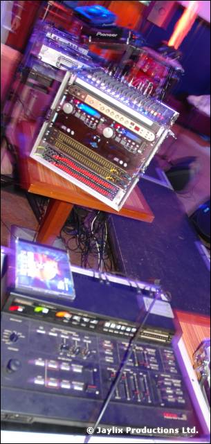 DJ equipment on a table, with a Pioneer mixer and rack unit above a dark sampler or mixing desk