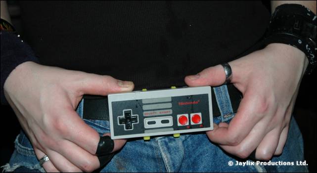 Hands holding a Nintendo controller at the waist of a pair of jeans