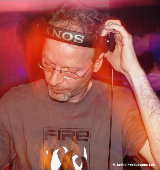 Close view of a man with glasses and a beard adjusting headphones, wearing a grey FIRE T-shirt