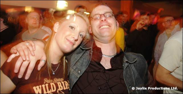 Two smiling people with arms around each other, one in a Wild Bird T-shirt and one in a denim jacket