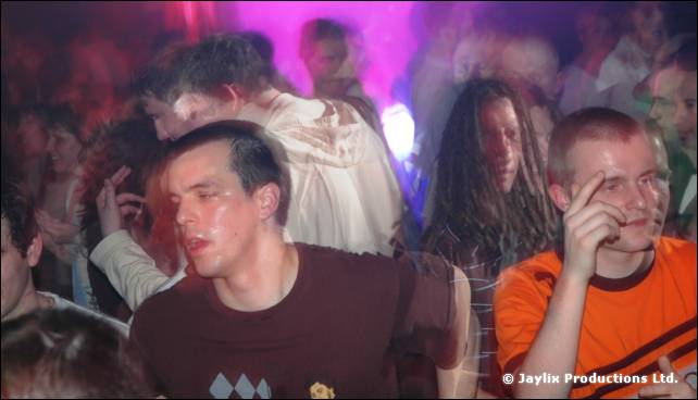 Close view of two men in a dancing crowd, one in a maroon T-shirt and one in orange, in blurred light