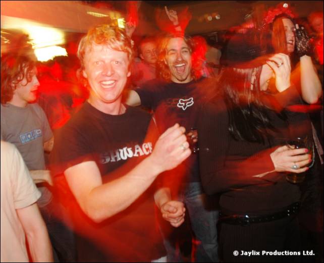 Smiling man in a black T-shirt dances in a red lit crowd