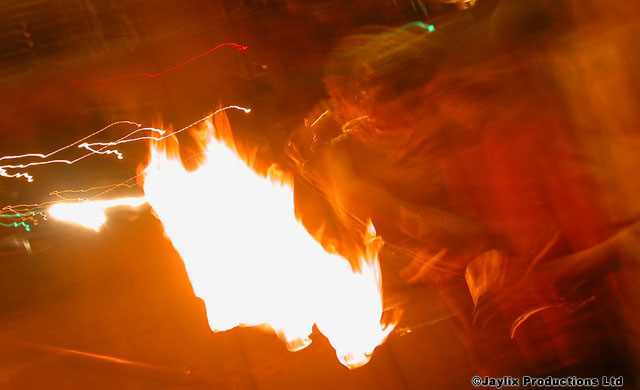 A bright flame streaks through a dark orange blurred scene
