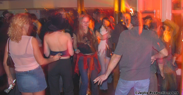 A crowd dances in a blurred, red lit room