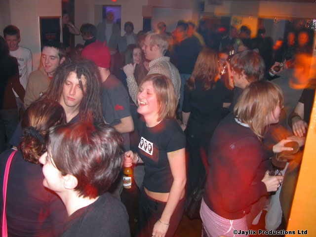 A crowd of people dance and laugh in a packed room