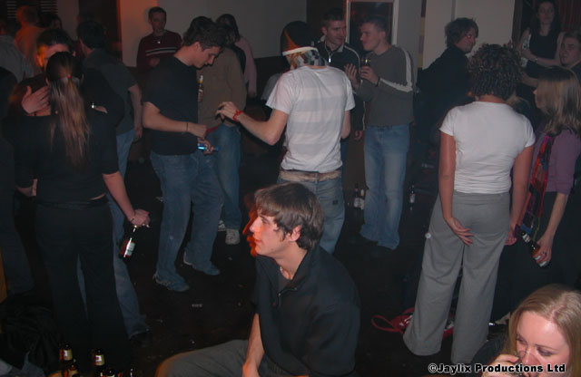 A crowd of dancers in a dim room, with a person sitting on the floor