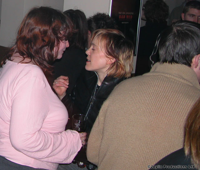 People stand close together in a busy bar, two women in the foreground