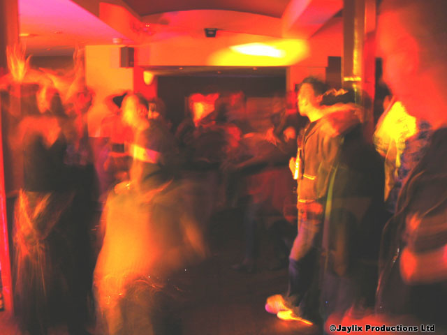 A blurred, dark dance floor with people moving under red and orange light