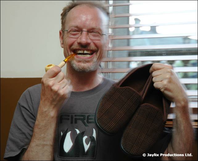 Smiling bearded man in a FIRE T-shirt holds a pair of slippers and a pipe
