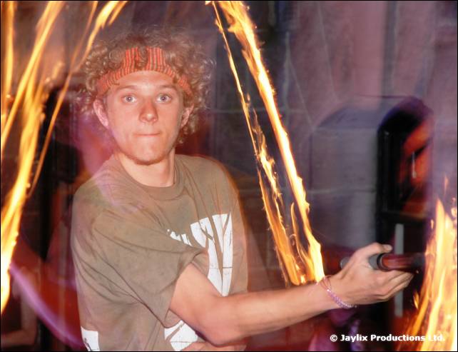 Young man with curly hair and a red headband holds a fire staff, with flame trails behind him