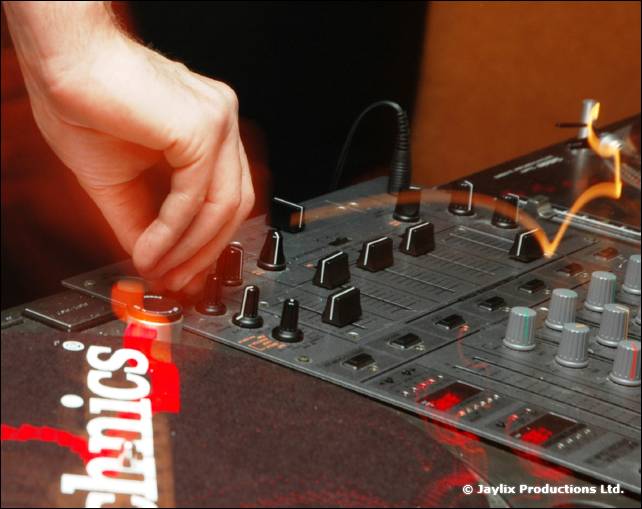Hand adjusts a knob on a DJ mixer beside a Technics turntable