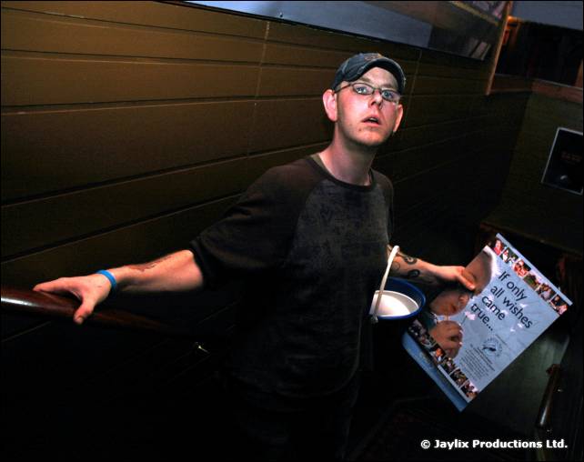 Man in a cap and glasses holds a flyer in a dark doorway