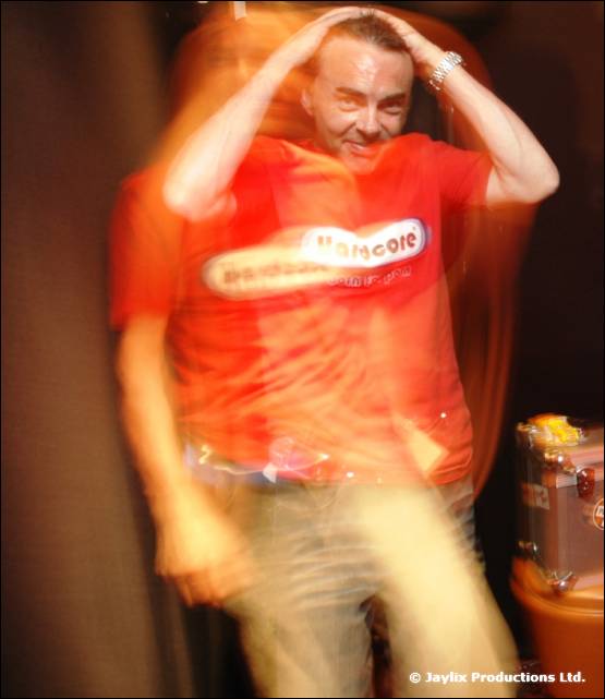 A blurred person in a red t-shirt holds both hands on their head in front of a flight case