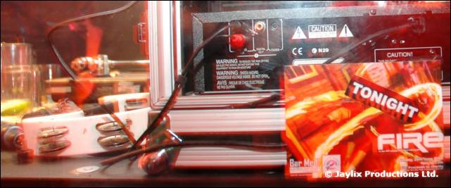Back of a DJ amplifier and cables with a FIRE flyer reading Tonight propped against it