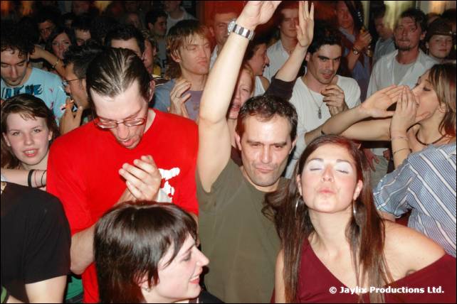 A packed crowd with raised arms, including a person in a red t-shirt and glasses