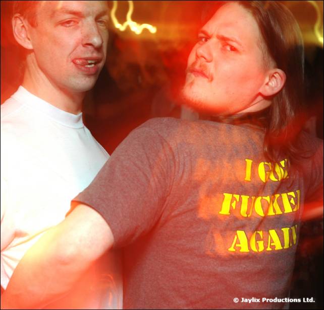 Two blurred men in a red light, one in a grey t-shirt with yellow text on it