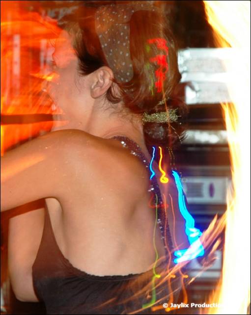 A blurred woman seen from behind with a sparkling hair clip and a bright flame at the right