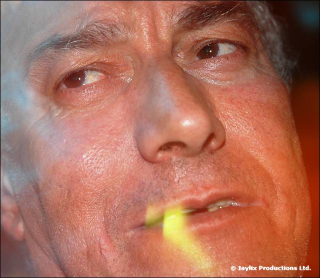 Extreme close-up of a man's face with a yellow glow stick between his lips