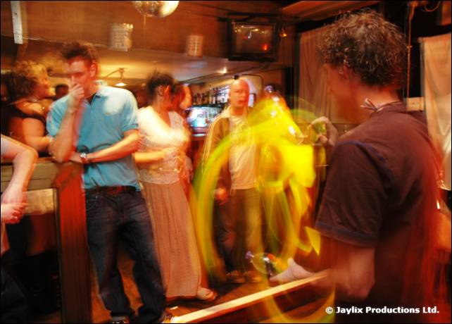 People stand at a bar with a blurred yellow fire trail at the centre