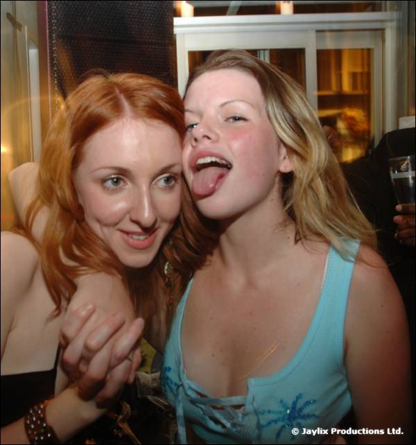 Two women pose together, one with red hair and one with blonde hair sticking out her tongue