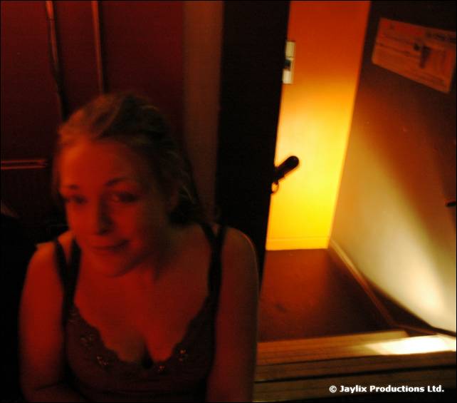 A woman in a dark top looks at the camera in a dimly lit stairwell