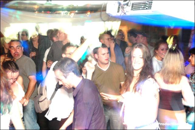 A crowded dance floor with people dancing under lights and a projector