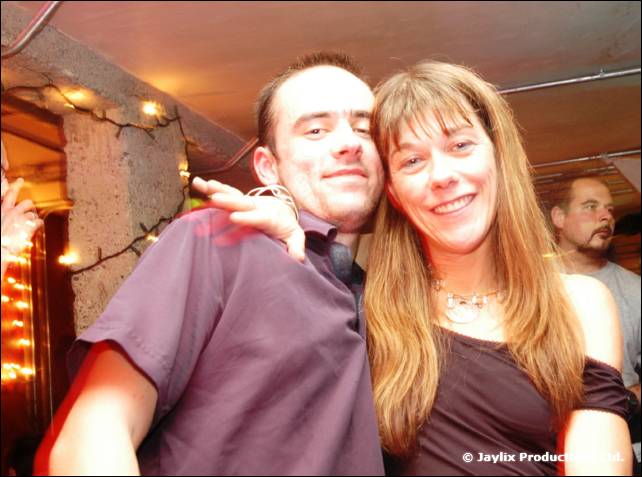 A man and a woman with long hair pose close together and smile in a bar