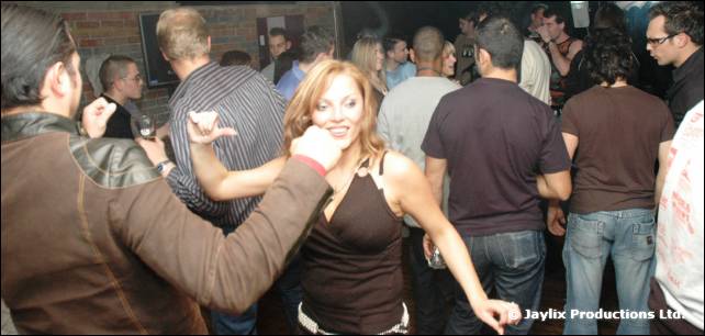 A woman with auburn hair dances beside a man with a dark T-shirt in a crowd