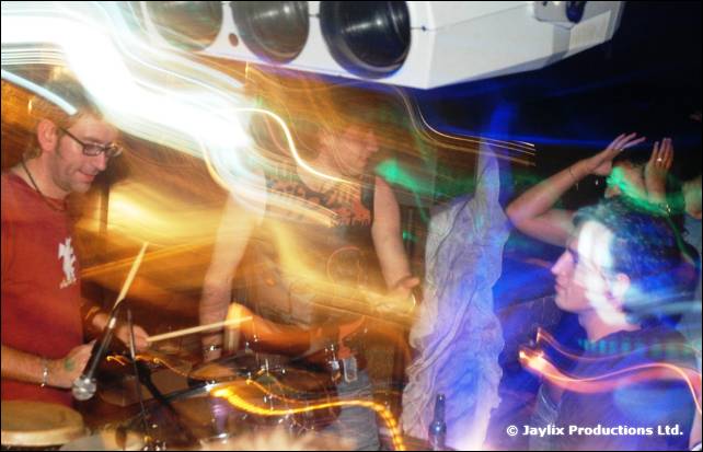 Percussion players in a blur of orange and blue light streaks, with a projector above