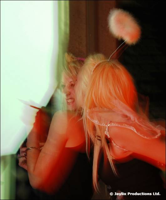 Two blonde people in fluffy costume ears and wings move in a blur of orange light