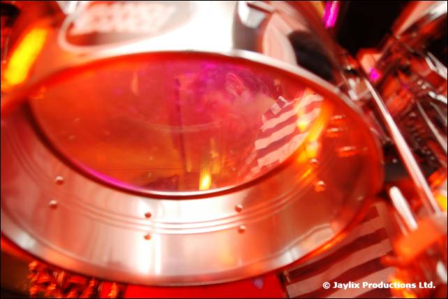 A close view of a silver drum rim and a striped sleeve in orange light