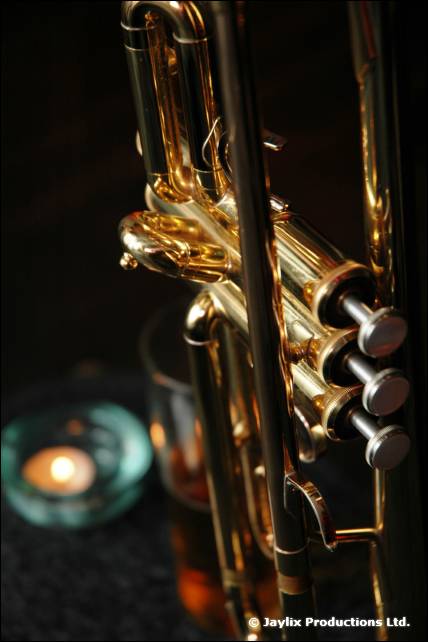 A trumpet valve section in gold beside a lit tea light