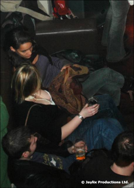 A woman in black sits on a sofa with other people, seen from above