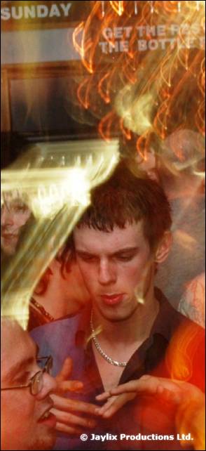 A young man looks down among blurred streaks of light and other people