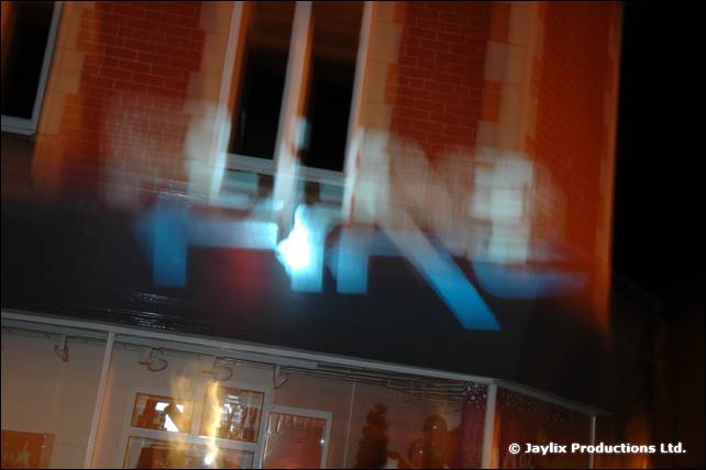 A blurred neon FIRE sign on a brick building at night