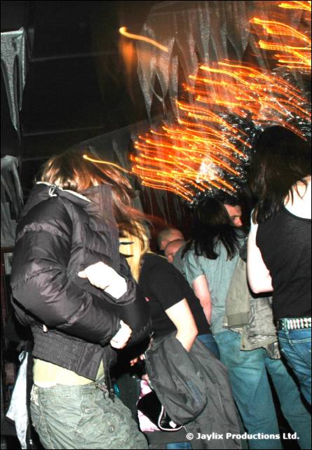 A person in a padded jacket moves through a crowd with streaks of orange light above
