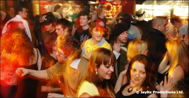 A busy dance floor in a bar with people dancing in warm light