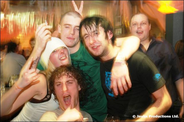 A group of people cheer and pile together, one wearing rabbit ears