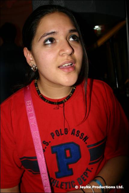 A person in a red T-shirt with a pink strap looks up and away from the camera