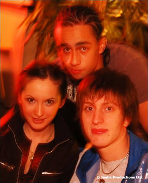 Three young people pose close together in warm orange light