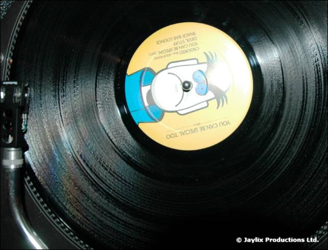 A close view of a vinyl record on a turntable with a yellow cartoon label